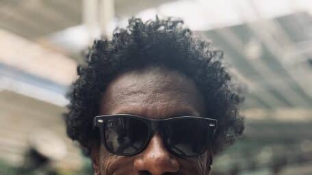 Brahim Snoopy, one of the directors of the documentary Khartoum, smiling and wearing sunglasses indoors.