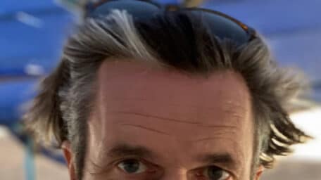 Phil Cox, one of the directors of the documentary Khartoum (2025), wearing a light blue shirt and sitting outdoors.