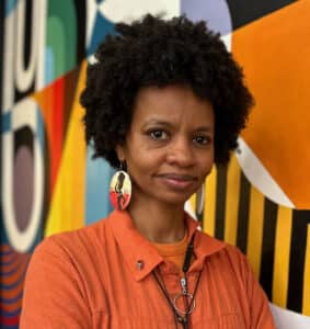 Rawia Alhag, one of the directors of the documentary Khartoum, smiling in front of a colorful background.