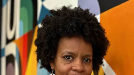 Rawia Alhag, one of the directors of the documentary Khartoum, smiling in front of a colorful background.