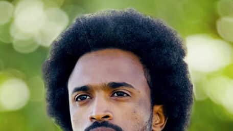 Timeea M. Ahmed, one of the directors of the documentary Khartoum, standing outdoors wearing a brown jacket and blue scarf.