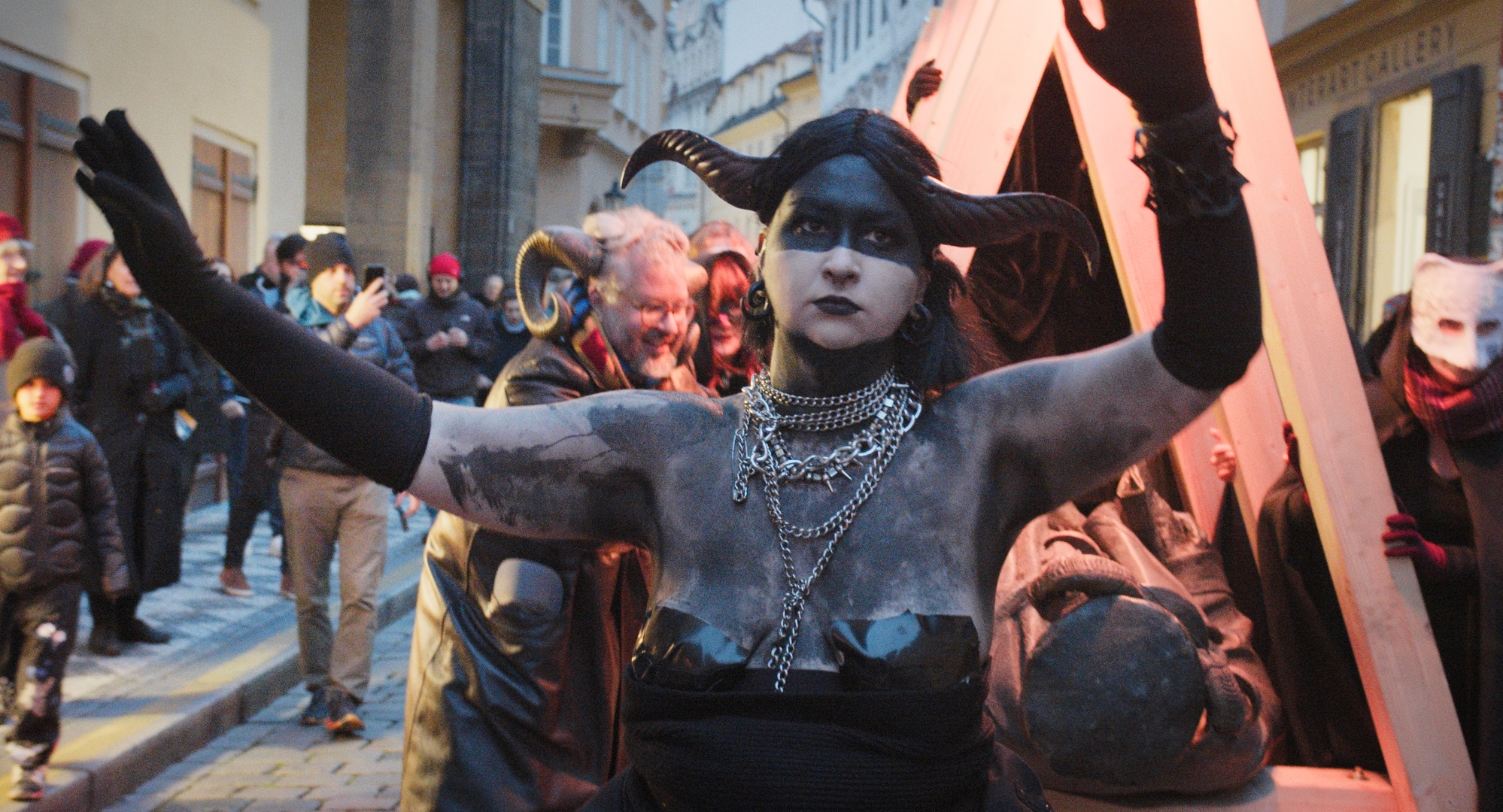 Scene from Urban Disobedience Toolkit showing a performer covered in clay raising their hand during a public demonstration.